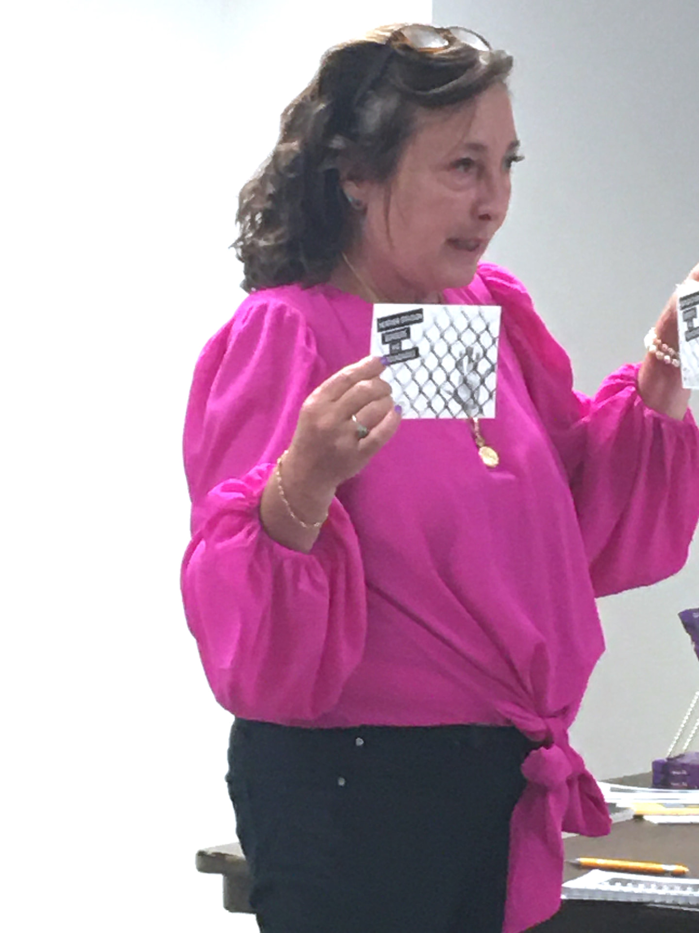 Elizabeth Levine reading poetry and holding an exhibition postcard