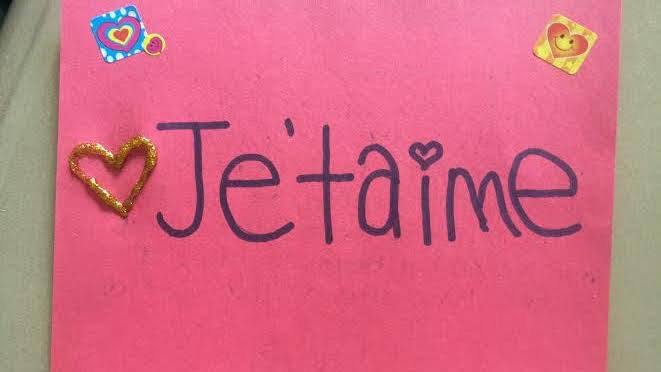 A pink handmade French card reading Je t’aime, decorated with hearts